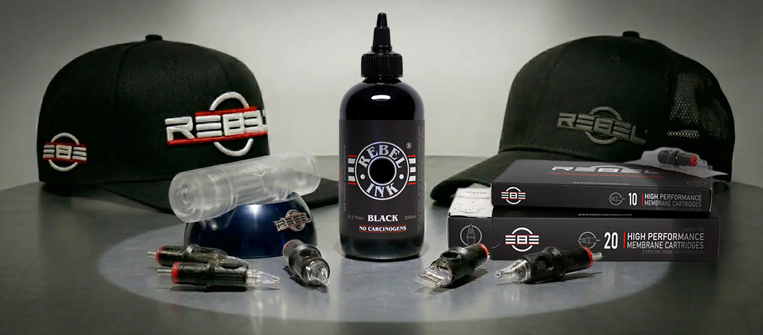 REBEL tattoo equipment including black tattoo ink, precision cartridge needles, and professional tattoo apparel and tools setup