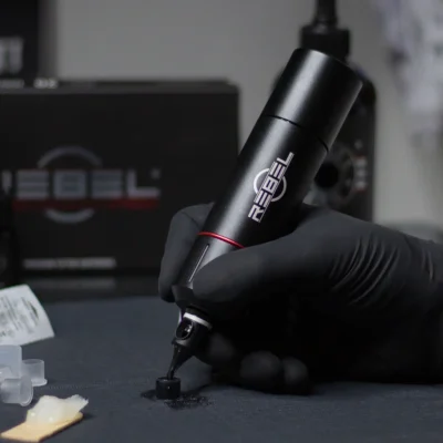 REBEL tattoo machine prototype in hand during R&D testing on work surface