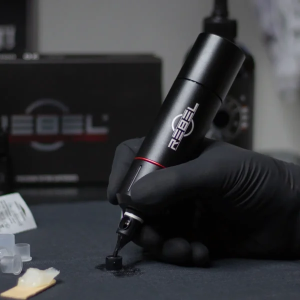 REBEL tattoo machine prototype in hand during R&D testing on work surface