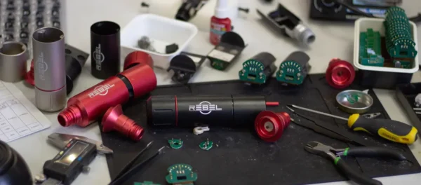 REBEL tattoo machine R&D workbench showing prototype parts, electronics, and tools during development