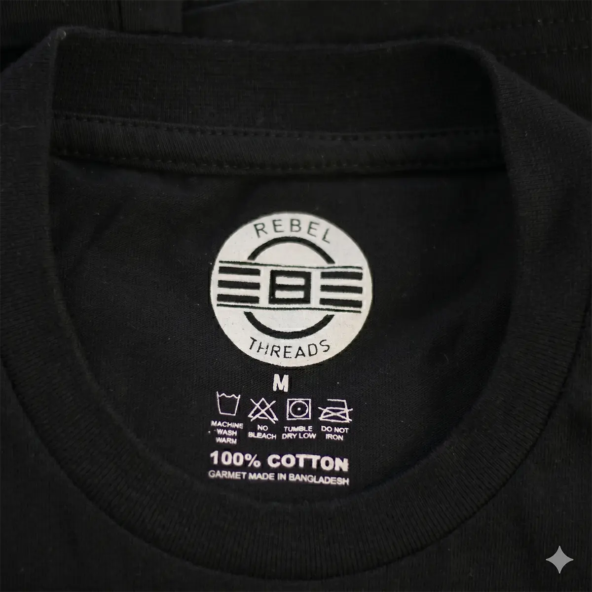 REBEL Precision Tee inside neck print showing REBEL Threads logo, 100% cotton, size M, care instructions