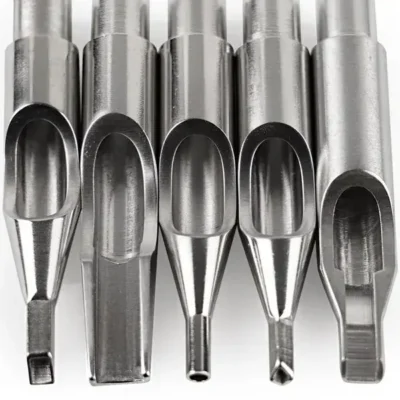Five vintage steel tattoo tips close-up — varying needle opening sizes, tapered shafts, square and round needle exits