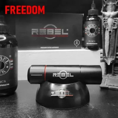 REBEL tattoo machine on holder with REBEL Black Ink and cartridge box — freedom through precision equipment